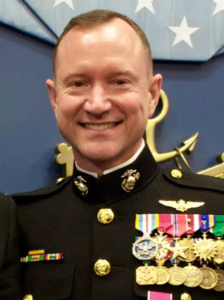 Bob Claypool smiling in a decorated military uniform with medals and pins, standing in front of a blue background.